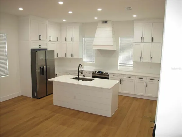 a kitchen with stainless steel appliances granite countertop a sink a stove a refrigerator and white cabinets