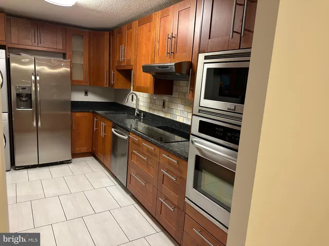 a kitchen with stainless steel appliances granite countertop a refrigerator and a stove