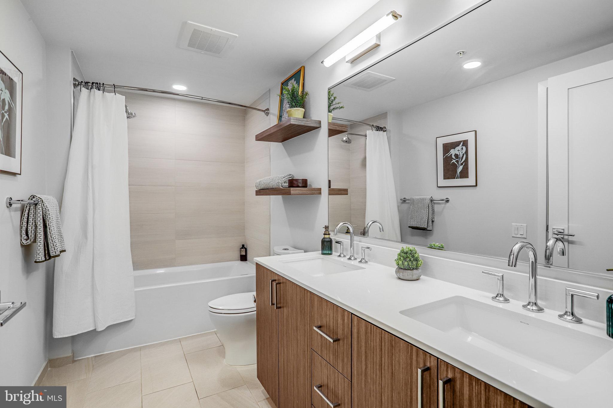 1211 Van Street Southeast, Unit 501 Washington, DC 20003 - Photo 9 of 37 a bathroom with a double vanity sink toilet mirror and shower
