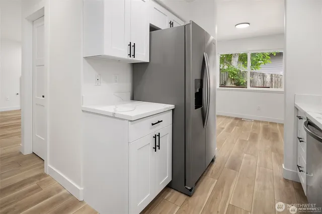 a kitchen with a refrigerator a sink and wooden floor