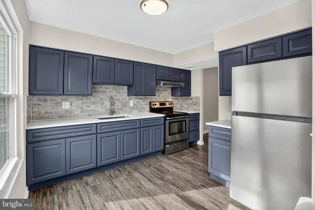 a kitchen with granite countertop a refrigerator stove top oven and sink
