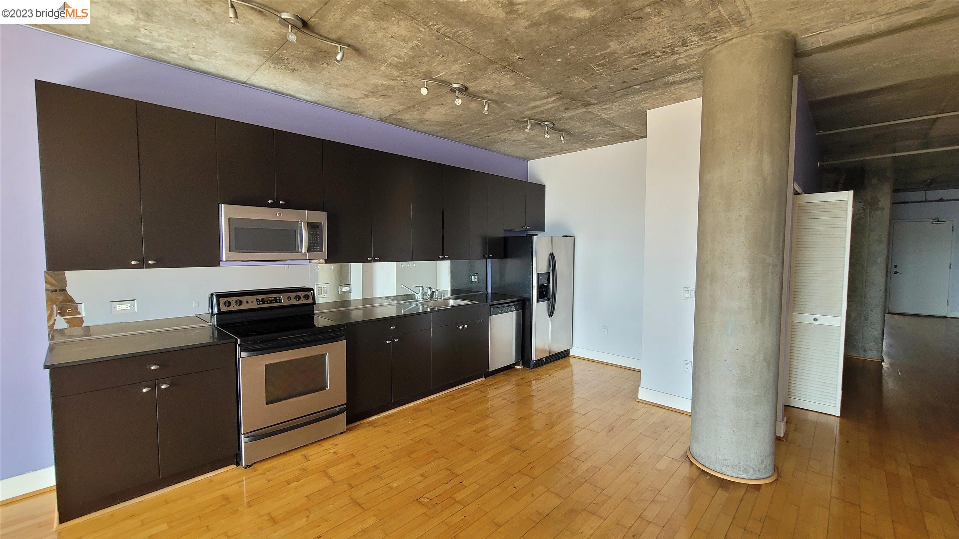 311 Oak Street, Unit 730 Oakland, CA 94607 - Photo 8 of 21 a kitchen with kitchen island stainless steel appliances a stove refrigerator and microwave