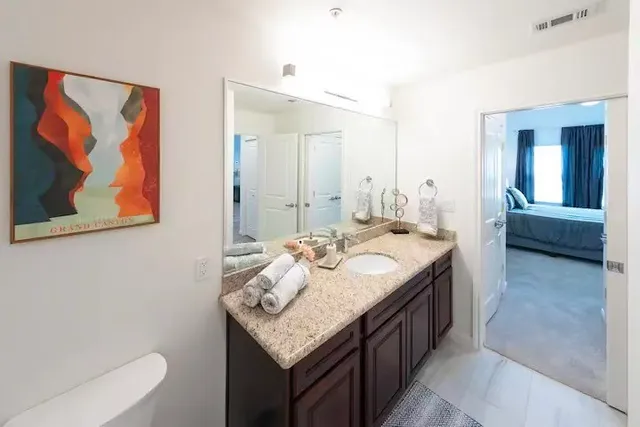 a en suite bathroom with a granite countertop sink and a mirror