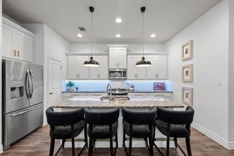 a large kitchen with kitchen island a sink stove and wooden floor