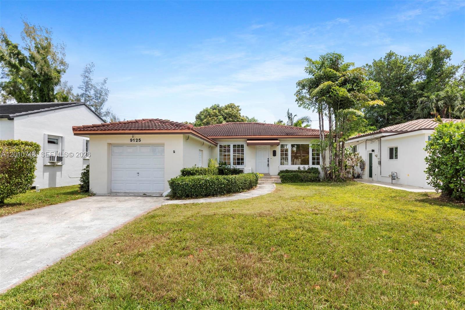 9125 Carlyle Avenue Surfside, FL 33154 - Photo 1 of 18 a front view of a house with a garden and yard