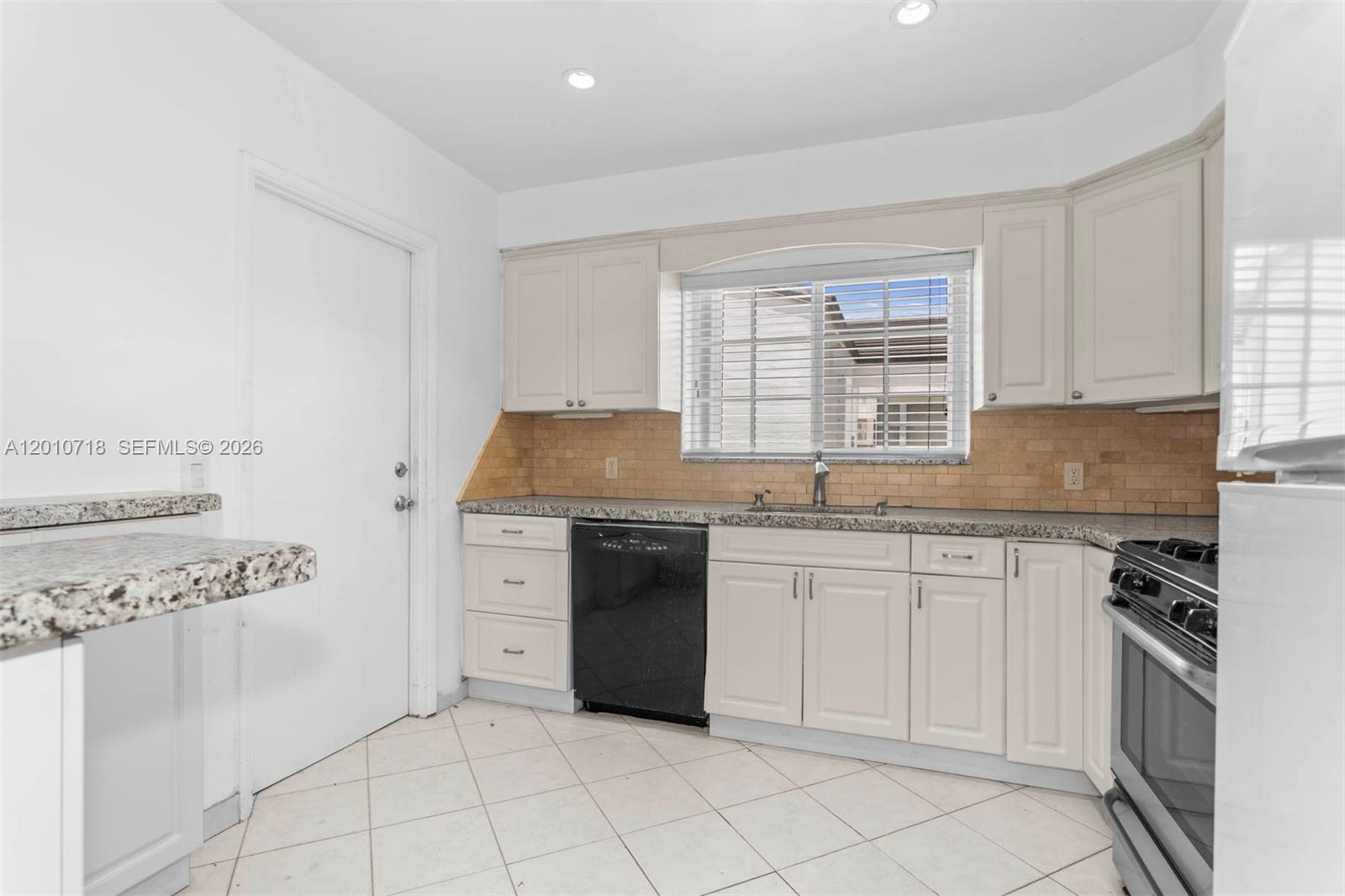9125 Carlyle Avenue Surfside, FL 33154 - Photo 5 of 18 a kitchen with granite countertop white cabinets and white appliances