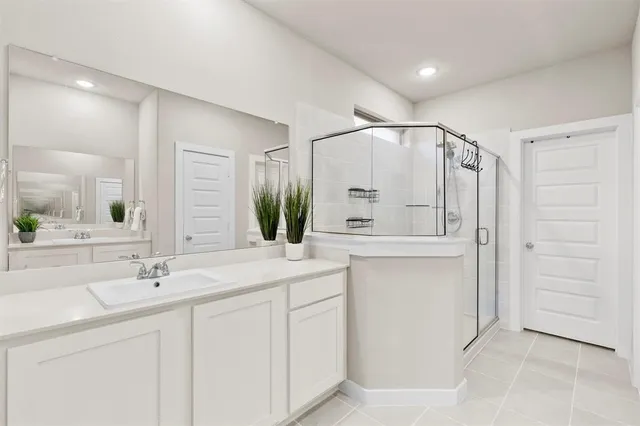 a en suite bathroom with a double vanity sink a mirror and next to a window