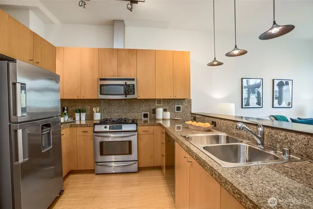 a kitchen with granite countertop a sink stainless steel appliances and cabinets