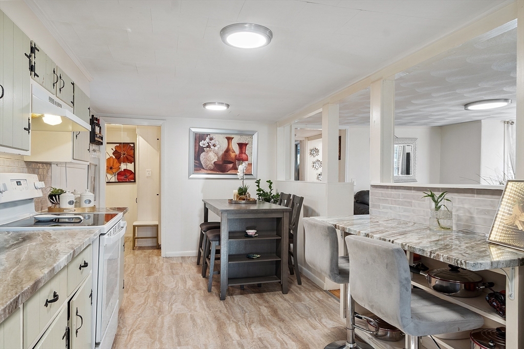 2 Grove Street Methuen, MA 01844 - Photo 8 of 38 a kitchen with stainless steel appliances kitchen island granite countertop a stove a refrigerator a dining table and chairs with wooden floor