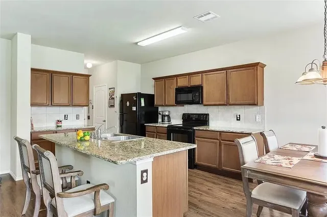 a kitchen with kitchen island granite countertop a sink appliances and cabinets