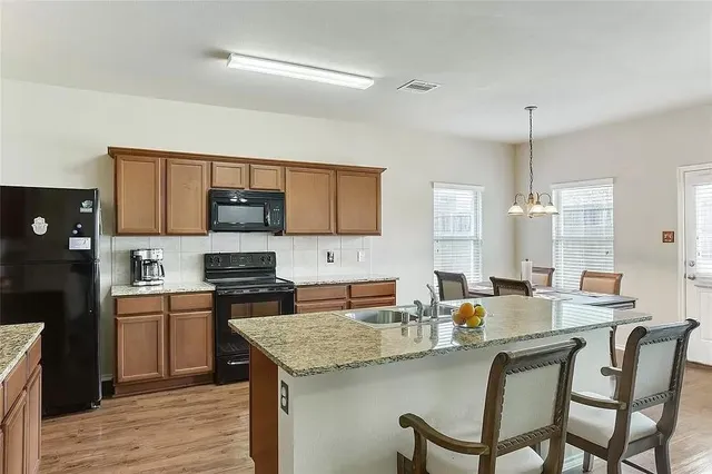 a kitchen with stainless steel appliances granite countertop a stove top oven a sink dishwasher and white cabinets with wooden floor