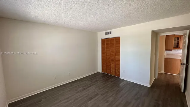 a view of an empty room with wooden floor and closet