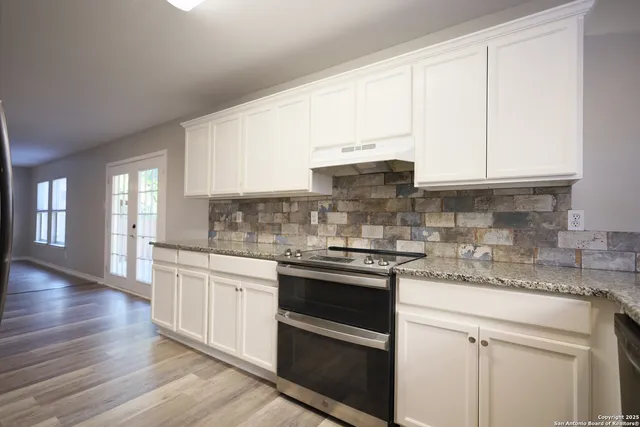 a kitchen with stainless steel appliances granite countertop a sink and cabinets with wooden floor