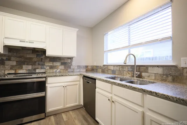 a kitchen with stainless steel appliances granite countertop a sink a stove and cabinets