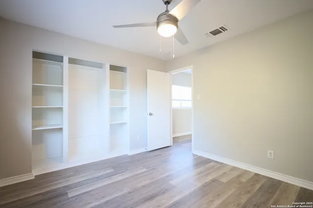 an empty room with wooden floor closet and windows