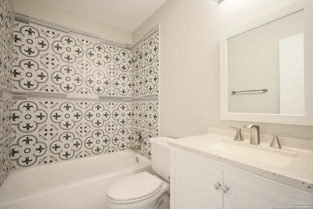 a bathroom with a bathtub sink vanity mirror and toilet