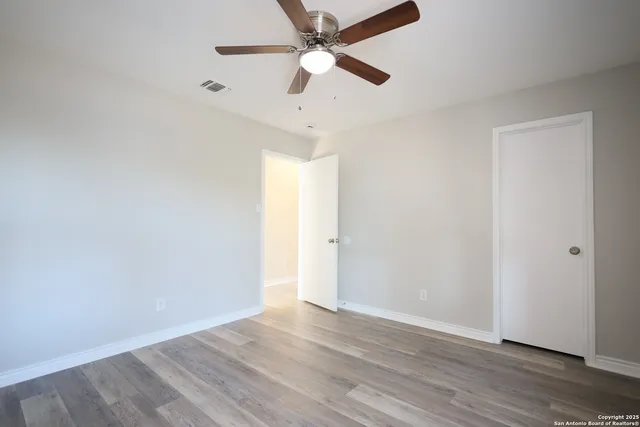 an empty room with wooden floor ceiling fan and a ceiling fan
