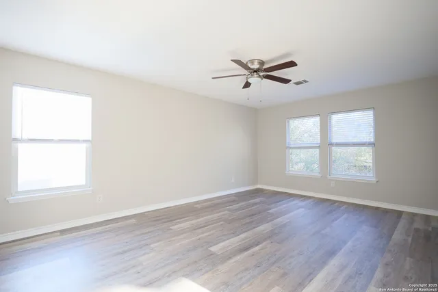 a view of empty room with wooden floor and fan