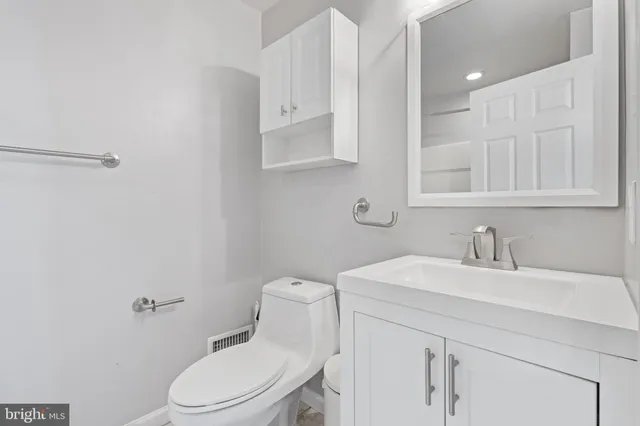 a bathroom with a toilet sink vanity and mirror