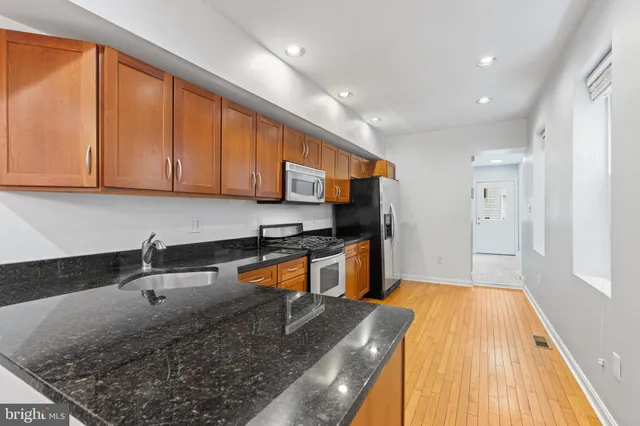 a kitchen with stainless steel appliances granite countertop a sink stove and refrigerator