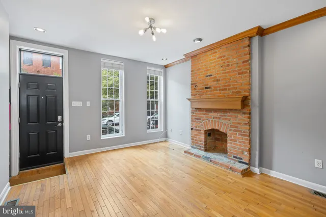 a view of empty room with fireplace and wooden floor