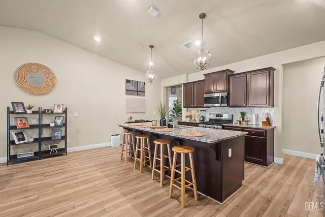 a kitchen with stainless steel appliances granite countertop a stove top oven a sink dishwasher and white cabinets with wooden floor