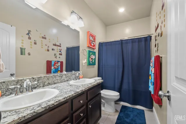 a bathroom with a granite countertop sink a toilet and a shower