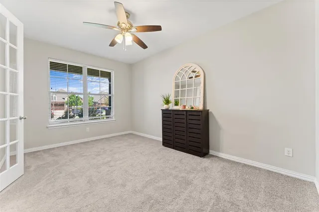 an empty room with windows and ceiling fan