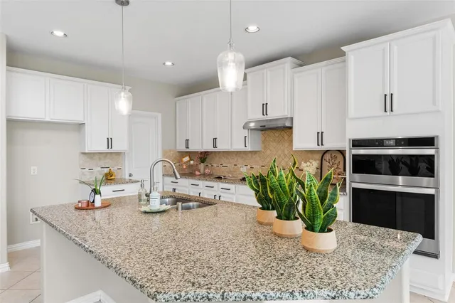 a kitchen with a stove a sink and a white cabinets