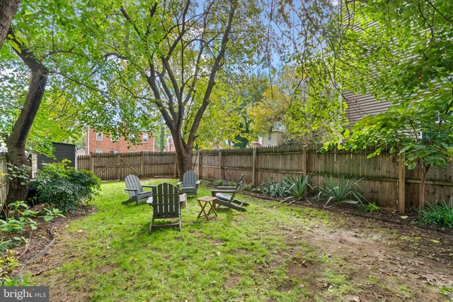 a view of backyard with table and chairs and large trees