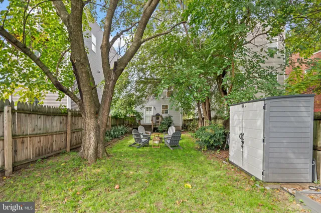 a view of a backyard with large tree and wooden fence