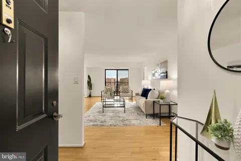 a living room with furniture wooden floor and a large mirror