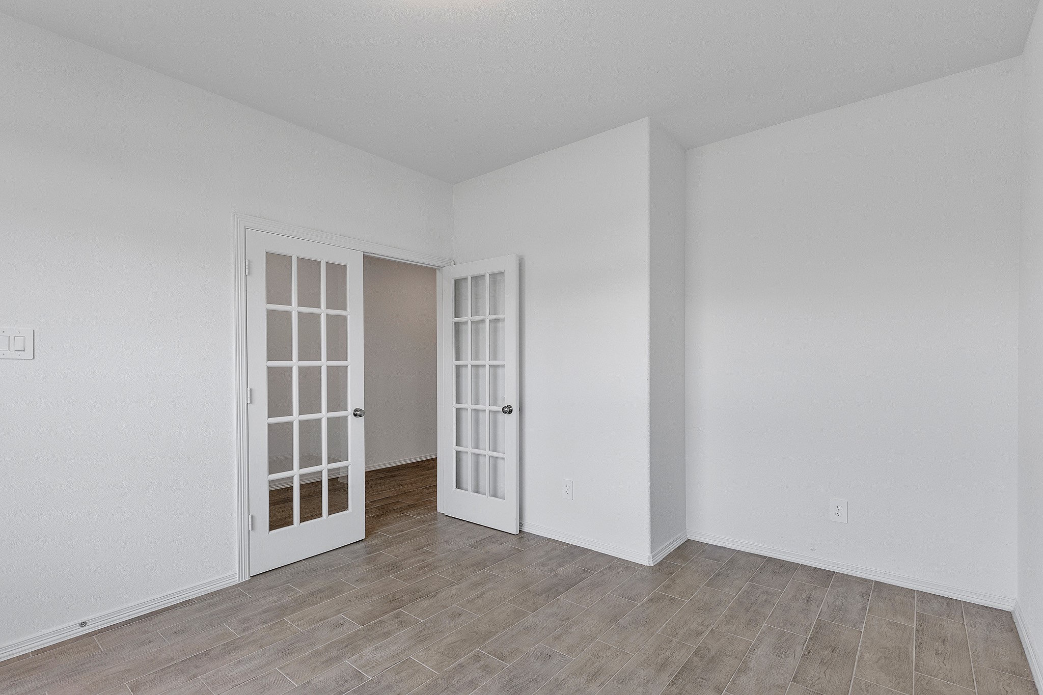 9658 Caney Trails Road Conroe, TX 77303 - Photo 12 of 50 an empty room with wooden floor and door