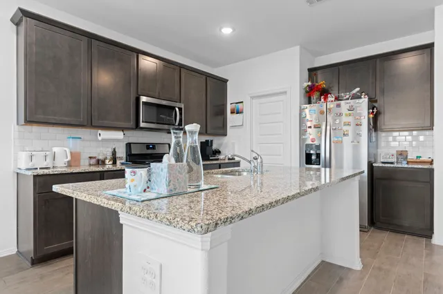 a kitchen with stainless steel appliances granite countertop a sink refrigerator and microwave