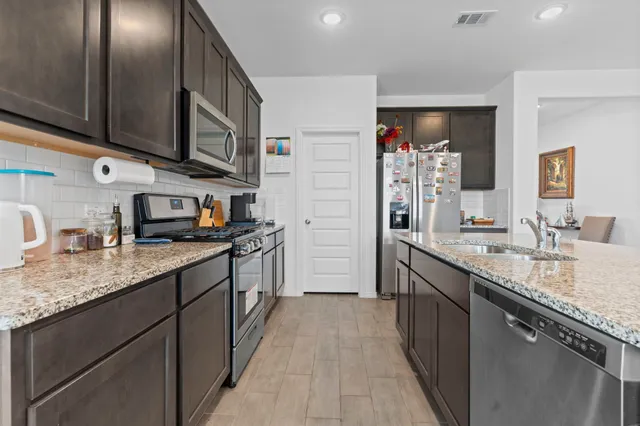 a kitchen with stainless steel appliances granite countertop a sink stove and refrigerator