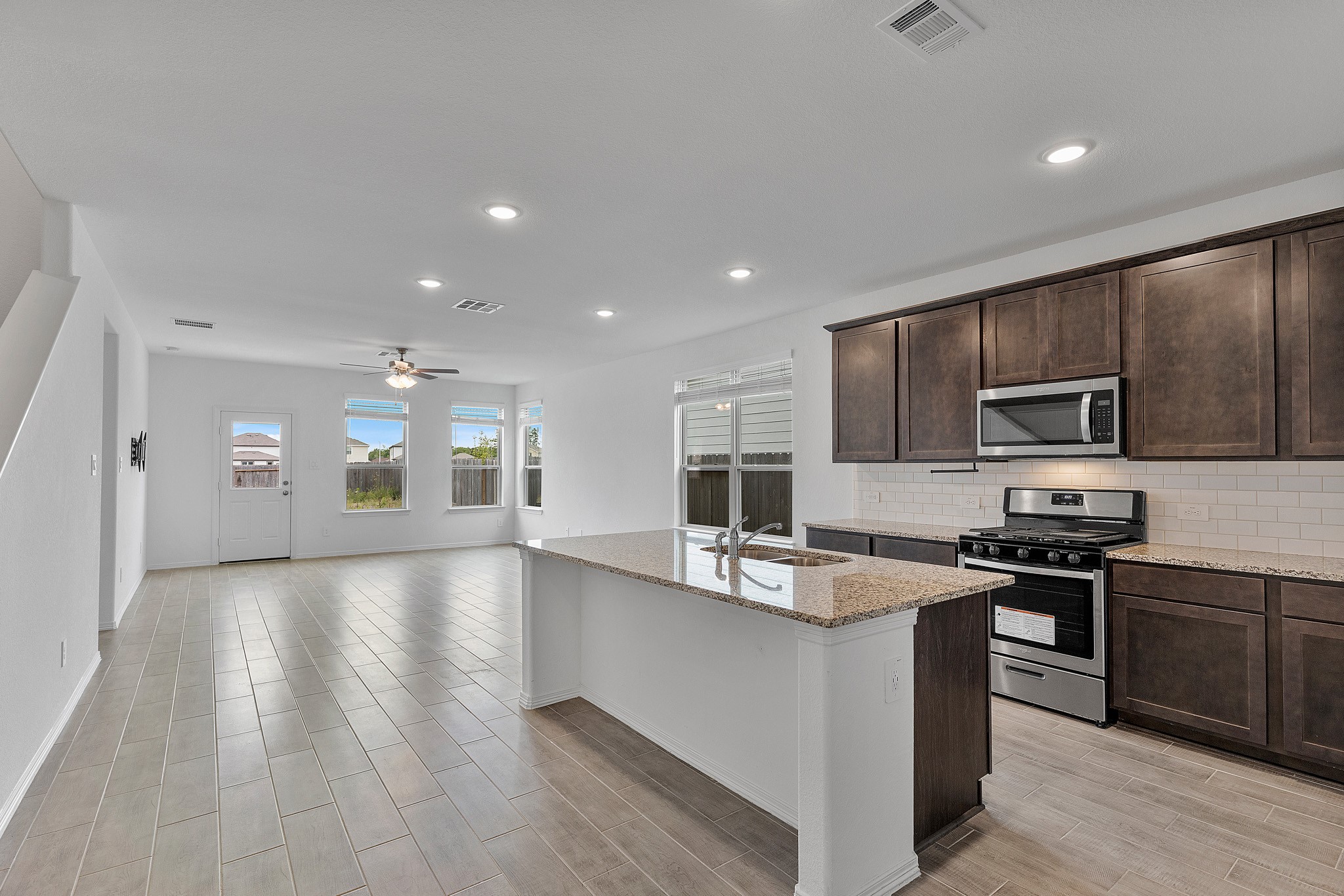 9658 Caney Trails Road Conroe, TX 77303 - Photo 2 of 50 a kitchen with stainless steel appliances granite countertop a sink dishwasher a stove top oven a refrigerator with grey cabinets and wooden floor