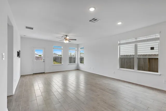 an empty room with wooden floor cabinet and windows