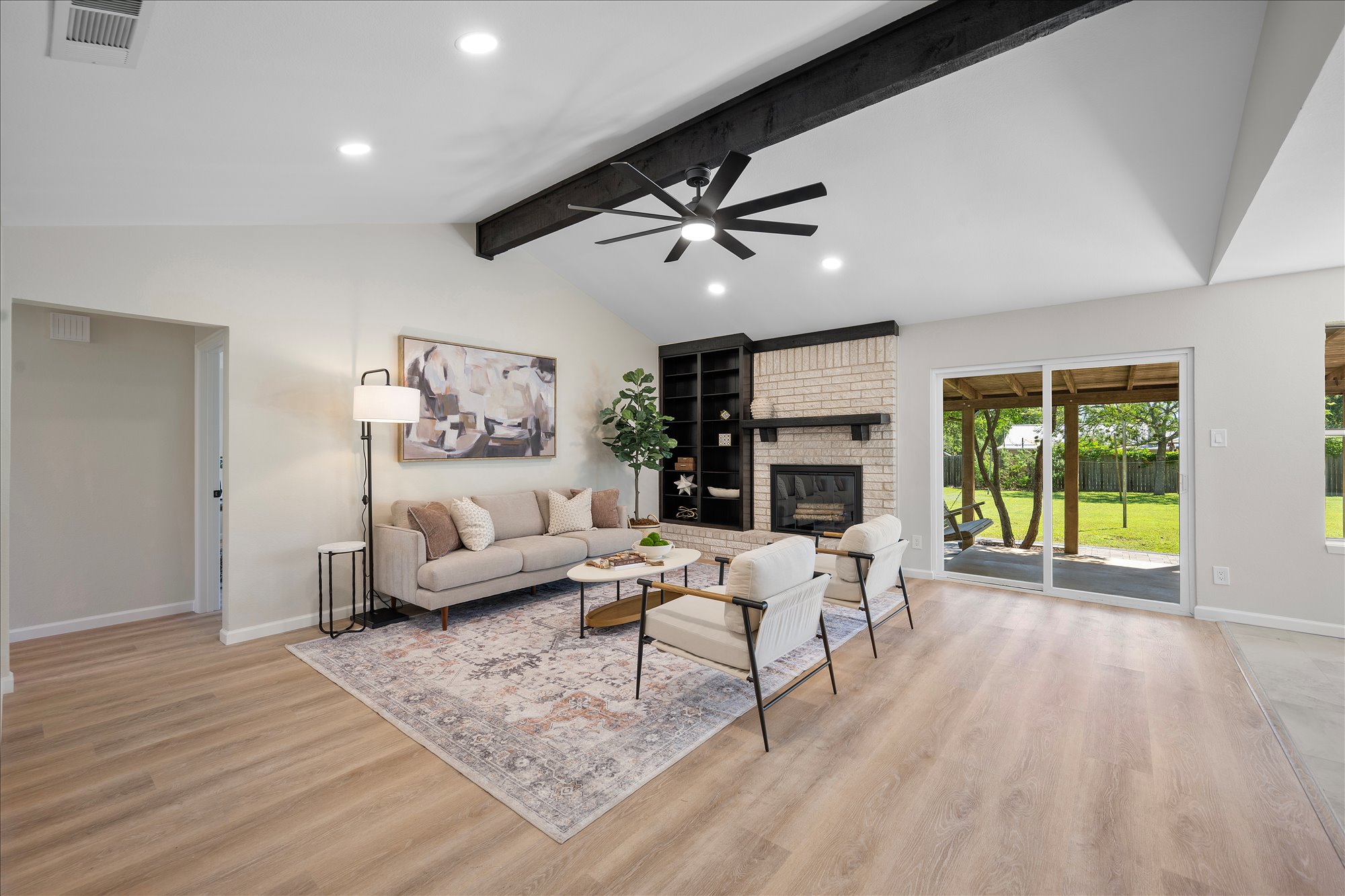 A comfortable living space boasts a brick fireplace, built-in shelving, and direct access to a private yard.