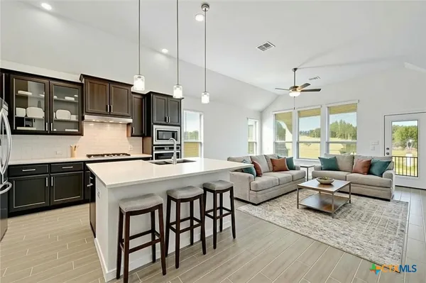 a kitchen with stainless steel appliances granite countertop a stove a refrigerator a oven a sink with island chairs and wooden floor