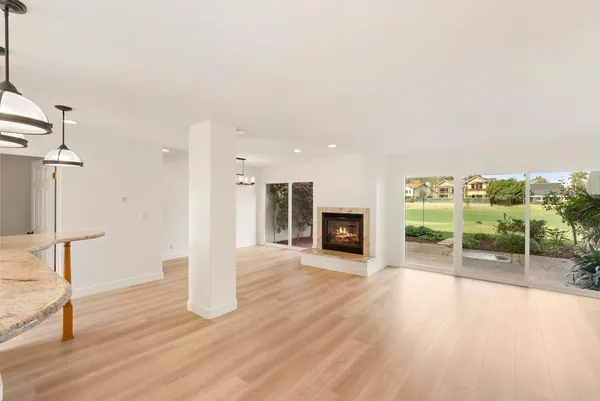 a view of an empty room with wooden floor fireplace and a window