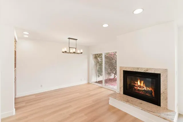 a view of a livingroom with a fireplace wooden floor and chandelier