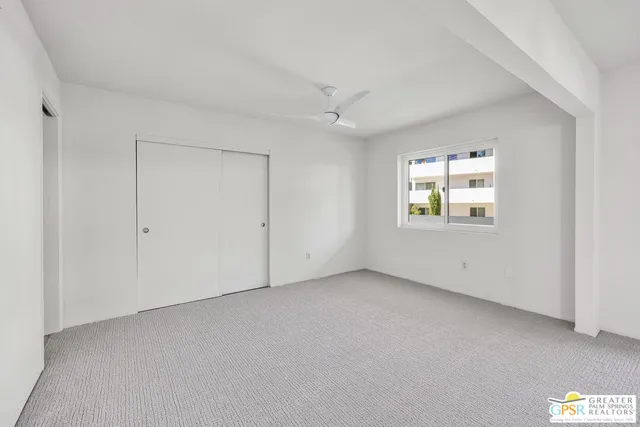 an empty room with a window and a ceiling fan