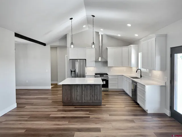 a large kitchen with a large counter top a sink stainless steel appliances and cabinets