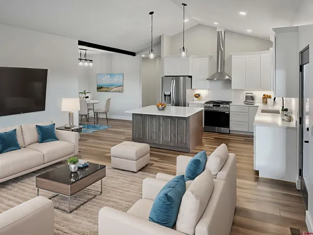 a living room with furniture kitchen area and a wooden floor
