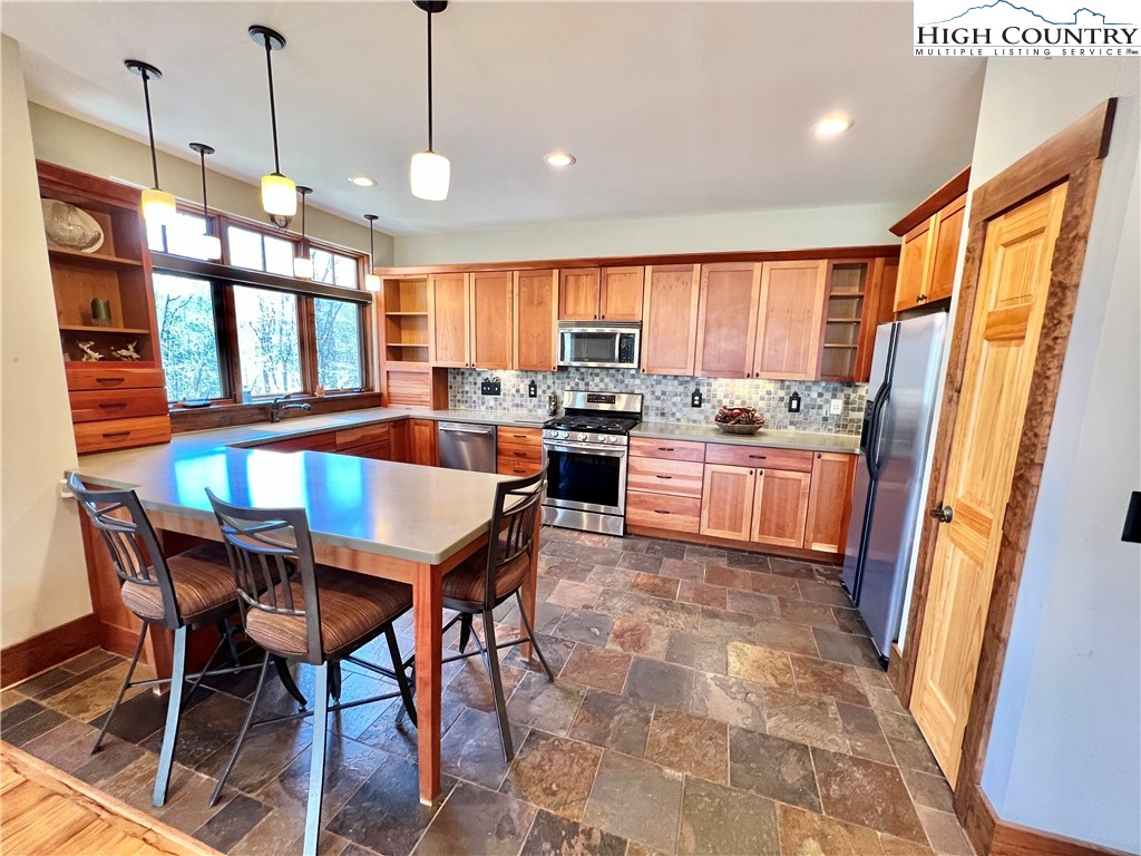 259 The Settlement Boone, NC 28607 - Photo 19 of 50 a kitchen with stainless steel appliances granite countertop a stove a sink dishwasher a dining table and chairs with wooden floor