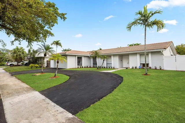 a front view of a house with a garden and palm trees