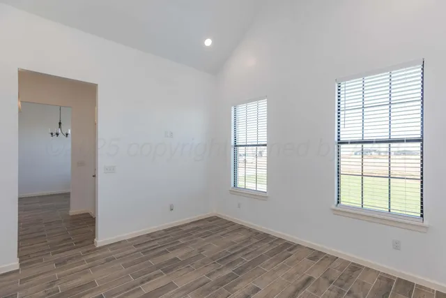 an empty room with wooden floor fan and windows