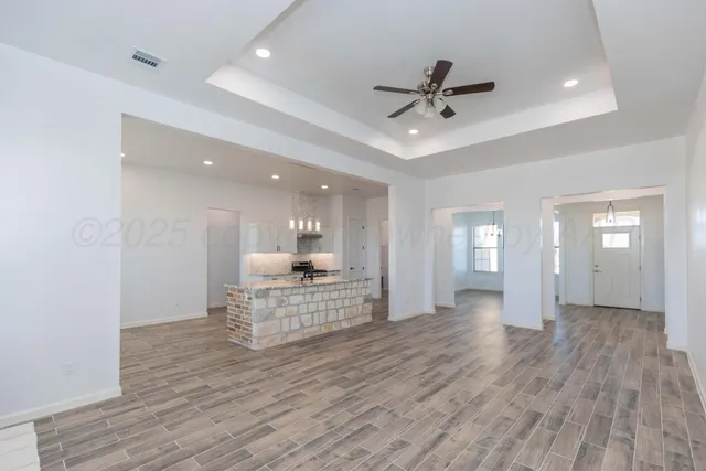 a view of a hallway with wooden floor and a ceiling fan