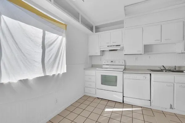 a kitchen with white cabinets appliances and a window