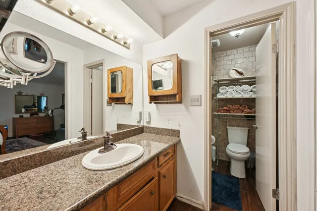 a bathroom with a granite countertop toilet a sink and a mirror
